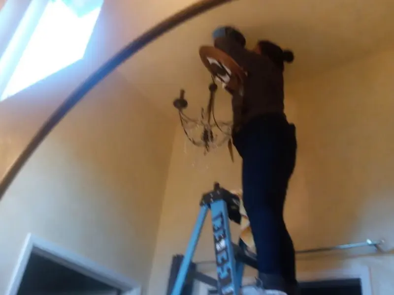 Electrician installing a chandelier in a Keyport residence